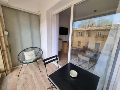 a balcony with a table and a chair and a window at Les studios d'Aurélia - Grand Théâtre de Provence in Aix-en-Provence