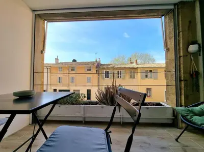 a table and chair in a room with a large window at Les studios d'Aurélia - Grand Théâtre de Provence in Aix-en-Provence