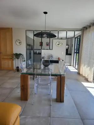 a dining room with a glass table and chairs at Appartement standing bord Sorgue in LʼIsle-sur-la-Sorgue