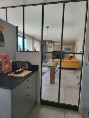 a kitchen with sliding glass doors leading to a dining room at Appartement standing bord Sorgue in LʼIsle-sur-la-Sorgue