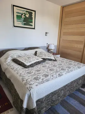 a bedroom with a bed with a blanket and a door at Appartement standing bord Sorgue in LʼIsle-sur-la-Sorgue
