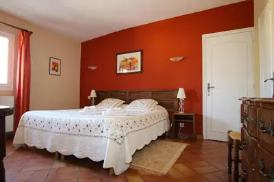 a bedroom with a large bed with red walls at Bastide Magnolia - Gite et chambres d 'hôtes Les dépendances, Roussillon in Roussillon