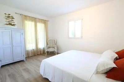 a white bedroom with a white bed and a chair at Bastide Magnolia - Gite et chambres d 'hôtes Les dépendances, Roussillon in Roussillon