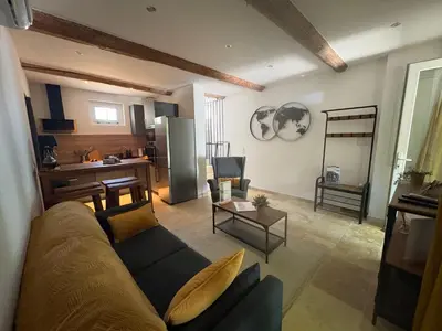 a living room with a couch and a kitchen at Le mas des glycines - parking privé et terrasse ombragée in Salon-de-Provence