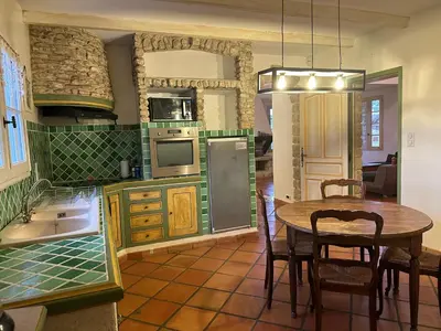 a kitchen with a table and a dining room at La Meynardière in Saint-Pierre-de-Vassols