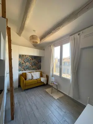 a living room with a yellow couch and a window at Beau studio au cœur d’Aix et du Cours Mirabeau in Aix-en-Provence