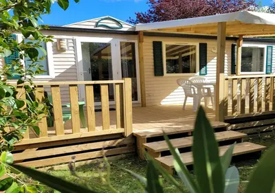 a house with a wooden deck with a table at Chez Coralie in La Roque-dʼAnthéron
