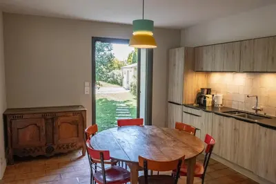 a kitchen with a table and chairs in a room at Le chant des jardins in LʼIsle-sur-la-Sorgue