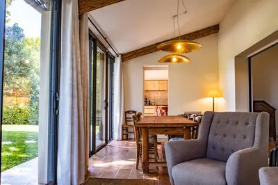 a living room with a table and chairs and a window at Le chant des jardins in LʼIsle-sur-la-Sorgue