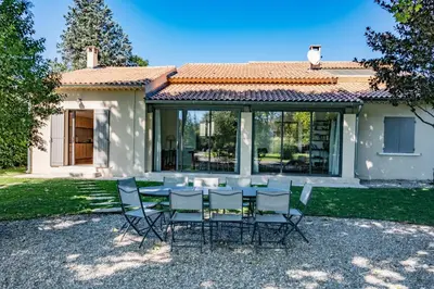 a table and chairs in front of a house at Le chant des jardins in LʼIsle-sur-la-Sorgue