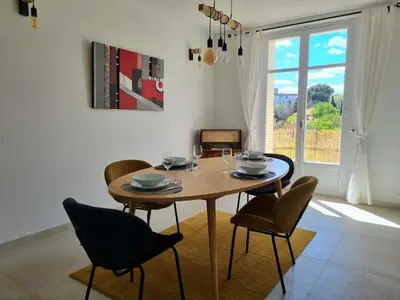 a dining room with a table and chairs and a window at Appartement spacieux de standing - parking gratuit in Aix-en-Provence