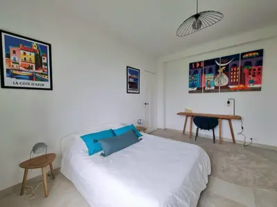 a bedroom with a white bed and a table at Appartement spacieux de standing - parking gratuit in Aix-en-Provence
