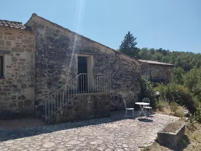 a stone building with a staircase and a table and chair at L' ABBADIE in Carniol
