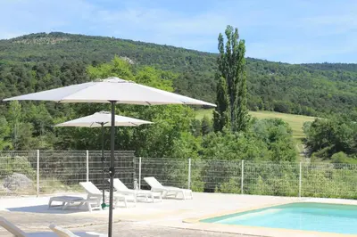 a white umbrella and chairs next to a swimming pool at L' ABBADIE in Carniol