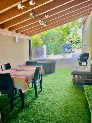 a patio with a table and chairs on the grass at Studio climatisé et tout équipé in Saint-Didier