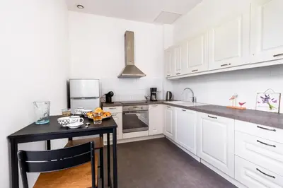 a kitchen with white cabinets and a black counter top at La Bastide des Joncquiers in LʼIsle-sur-la-Sorgue