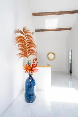 a blue vase with a plant in a room at La Bastide des Joncquiers in LʼIsle-sur-la-Sorgue