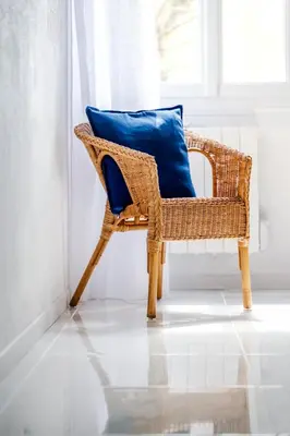 a wicker chair with a blue pillow in a room at La Bastide des Joncquiers in LʼIsle-sur-la-Sorgue