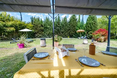 a wooden table with plates on it in a yard at La Bastide des Joncquiers in LʼIsle-sur-la-Sorgue