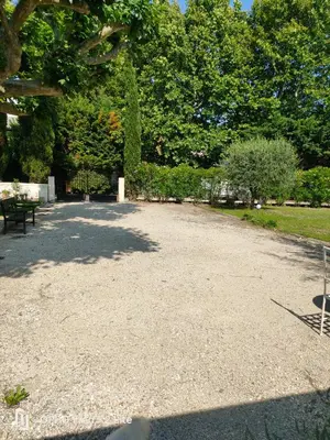 a gravel driveway with benches and trees in a park at La Bastide des Joncquiers in LʼIsle-sur-la-Sorgue