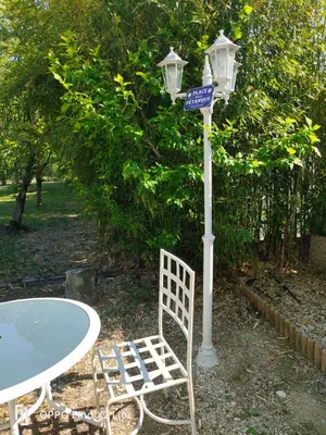a table and a street light with a chair and a street sign at La Bastide des Joncquiers in LʼIsle-sur-la-Sorgue
