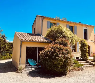 a house with a table and a chair in front of it at Magnifique villa -piscine privée vue Mont Ventoux in Malemort-du-Comtat