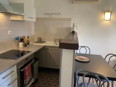 a kitchen with a counter and a sink and a table at Jolie petite maison Avignon - Montfavet in Montfavet