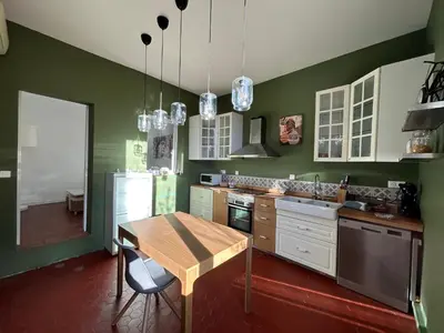 a kitchen with green walls and a wooden table at UN MOMENT SUSPENDU in Aix-en-Provence