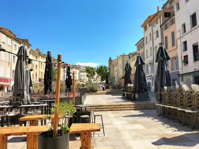a street with tables and umbrellas in a city at CORDELIERS MAIRIE in Aix-en-Provence